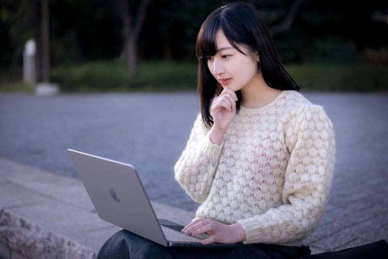 パソコンを膝において考える女性